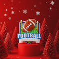 Load image into Gallery viewer, Personalized football Christmas ornament featuring a brown football with stitched details on a shield style background and goalpost design, customizable name area on the front banner and customizable year area on the football, glossy finish with raised 3D front details and flat 2D back, white hanging ribbon, displayed on a snowy football field themed holiday background with pine branches and festive decorations.

