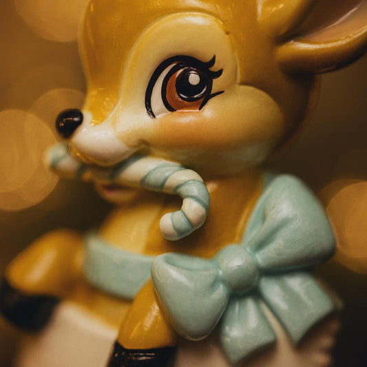 A glossy resin baby deer ornament features a cute fawn character sitting inside a soft pastel blue winter boot, holding a striped candy cane, with gentle antler details, smooth painted cartoon style finish, soft holiday lighting and blurred festive background, handwritten personalization showing the baby name on the boot and the year or Baby’s First Christmas text below, designed as a mostly 2D ornament with raised 3D details on the front only.