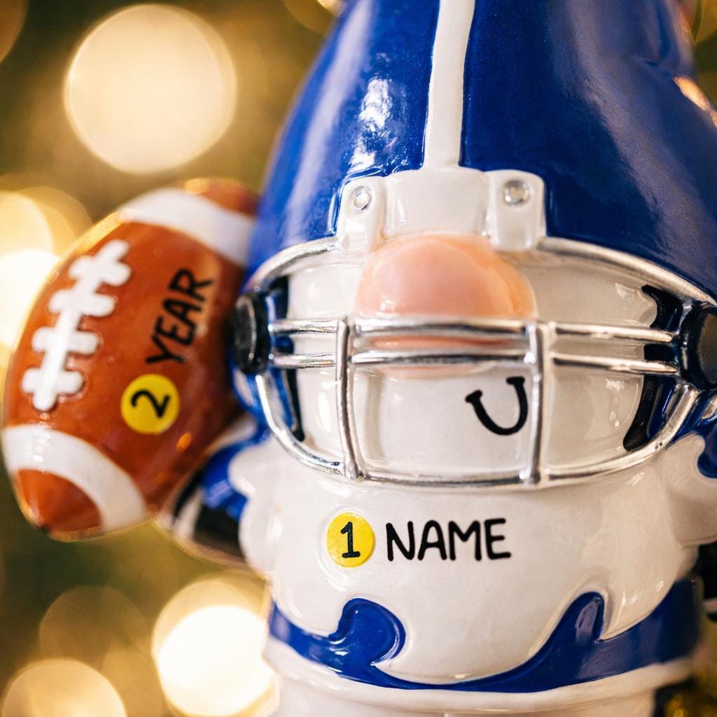 Personalized football gnome Christmas ornament featuring a blue and white gnome character wearing a football helmet and holding a football, customizable name area on the front body and customizable year area on the football, glossy finish with raised 3D front details and flat 2D back, white hanging ribbon, displayed on a snowy football field themed holiday background with pine branches and festive decorations.