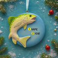 Load image into Gallery viewer, Trout Fish-shaped ornament with customizable name and year on a blue background with Christmas decorations.
