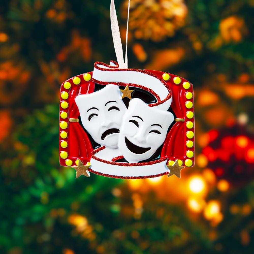 Decorative Christmas ornament with theatrical masks on a blurred Christmas tree background