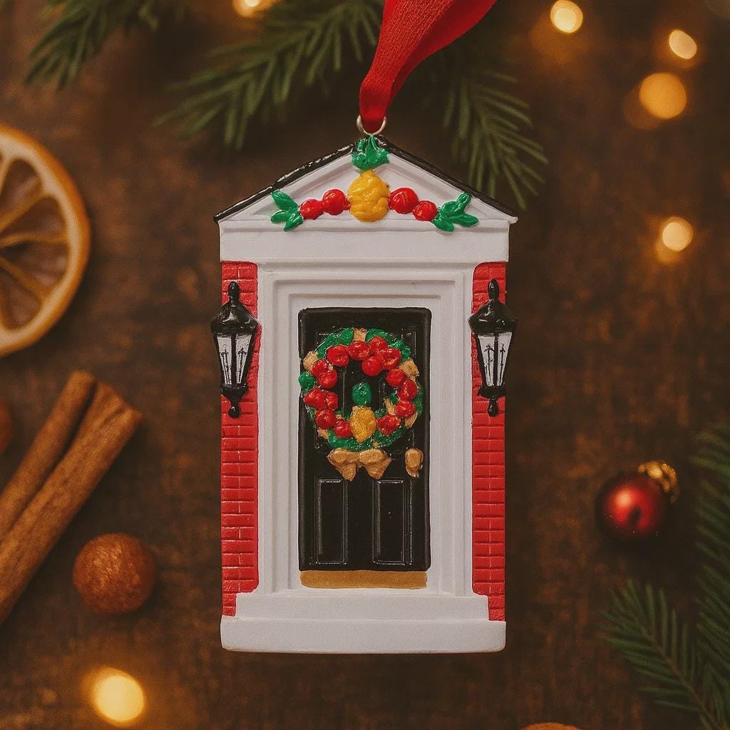 Decorative Christmas ornament of a door with a wreath, surrounded by festive items on a wooden surface.