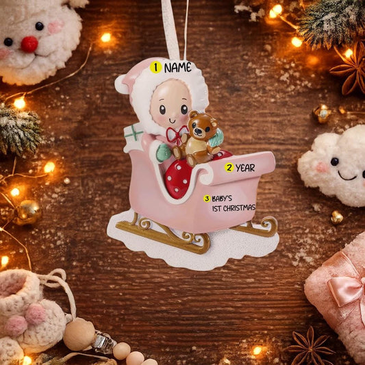 Personalized baby first Christmas ornament featuring a sweet baby sitting in a pastel pink sleigh holding a teddy bear. Handwritten baby name and year or Baby’s First Christmas text shown on the sleigh. Smooth resin finish with soft pastel tones, lightweight structure, mostly 2D ornament with raised 3D front details, designed for baby nursery themed Christmas tree decor and keepsake gifting.