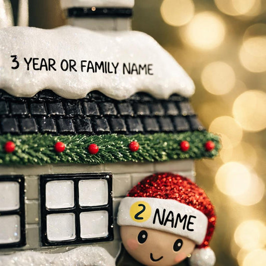 Personalized Christmas house ornament featuring a cozy winter home decorated with snow, wreaths, garlands, and festive details. Two smiling characters wearing Santa hats peek from the front, each customizable with a name, while the roof displays a year or family name. Designed with a detailed 3D raised front and smooth finish, this ornament is perfect for Christmas tree decor, family keepsakes, new home celebrations, and holiday gifting.

