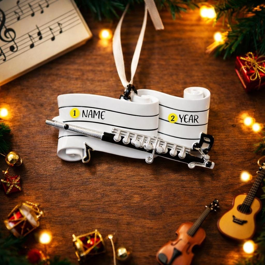 Music-themed ornament with name and year fields on a wooden surface with Christmas decorations.
