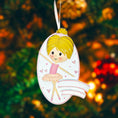 Load image into Gallery viewer, Personalized ballet girl Christmas ornament featuring a cute ballerina character in a pink tutu dress with heart details, customizable name area on the front banner and customizable year area below, glossy finish with raised 3D front details and flat 2D back, white hanging ribbon, displayed on a snowy holiday background with pine branches and festive decorations.
