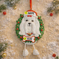 Load image into Gallery viewer, Decorative Christmas ornament with a white Maltese dog in a wreath on a textured surface with holiday decorations.
