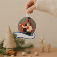 Load image into Gallery viewer, Decorative Christmas ornament with a boxer design held by a hand, surrounded by festive items on a neutral background.
