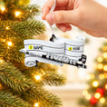 Load image into Gallery viewer, Hand holding a personalized sleigh ornament with Christmas lights in the background
