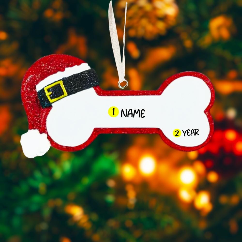 Personalized dog Christmas ornament featuring a bone shaped design with a glitter red Santa hat detail on one end, customizable name area centered on the ornament and customizable year displayed on the opposite side, smooth glossy finish with glitter accents, flat lightweight structure and red hanging ribbon, photographed on a snowy holiday styled background with pine branches, festive Christmas ornaments, dog themed props, and warm seasonal lighting for pet lovers.