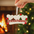 Load image into Gallery viewer, Decorative ornament with 'grandchildren' text held by a hand against a festive background.
