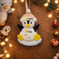 Load image into Gallery viewer, Personalized Baby Penguin First Christmas Ornament featuring a sweet penguin wearing a soft pink winter hat, sitting on a snowy base. The baby’s name is displayed on the hat and the year is placed on the belly, creating a meaningful keepsake for a newborn’s first holiday season. With bright yellow feet, soft winter details, and charming 3D design, this ornament is perfect for baby girls celebrating their very first Christmas and makes a thoughtful holiday gift for new parents.
