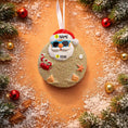 Load image into Gallery viewer, Decorative Christmas ornament with Santa Claus face, surrounded by festive decorations on a sandy background.
