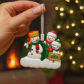 Load image into Gallery viewer, Decorative Christmas ornament with snowmen and a sign, held by a hand against a festive background.
