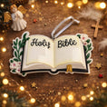 Load image into Gallery viewer, Personalized Holy Bible Christmas Ornament featuring an open scripture design with elegant “Holy Bible” lettering across the pages. The left page is customized with a name and the right page displays the year, creating a meaningful faith based keepsake. Surrounded by soft greenery and delicate flowers, this religious ornament is perfect for baptisms, baby dedications, first communions, or celebrating a Christ centered Christmas. A thoughtful spiritual gift for families who cherish their faith.
