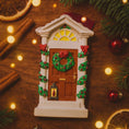 Load image into Gallery viewer, Decorative Christmas door ornament with wreath on a wooden surface with lights and cinnamon sticks.

