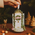 Load image into Gallery viewer, Decorative Christmas ornament of a door with wreath and candy cane, held by a hand.
