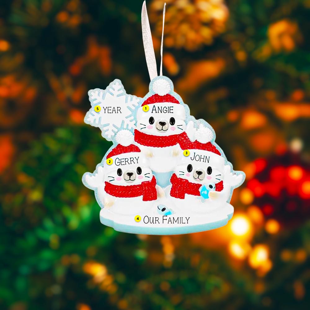 Personalized Christmas ornament with family of 3 seal in red sweaters against a blurred Christmas tree background.