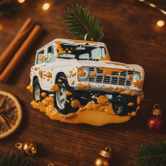 Decorative Christmas ornament shaped like a white SUV with orange mud splashes on a wooden surface.