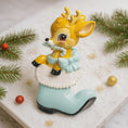 Load image into Gallery viewer, A glossy resin baby deer ornament features a cute fawn character sitting inside a soft pastel blue winter boot, holding a striped candy cane, with gentle antler details, smooth painted cartoon style finish, soft holiday lighting and blurred festive background, handwritten personalization showing the baby name on the boot and the year or Baby’s First Christmas text below, designed as a mostly 2D ornament with raised 3D details on the front only.

