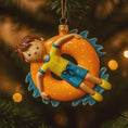 Load image into Gallery viewer, Decorative ornament of a boy on an inner tube with a Christmas tree background
