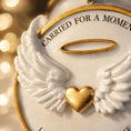 Load image into Gallery viewer, Decorative angel wing ornament with a gold heart and 'Carried for a Moment' text on a blurred background.
