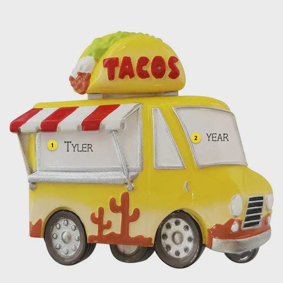 Toy taco truck with 'TACOS' on top, yellow body, red and white striped roof, and cactus design.