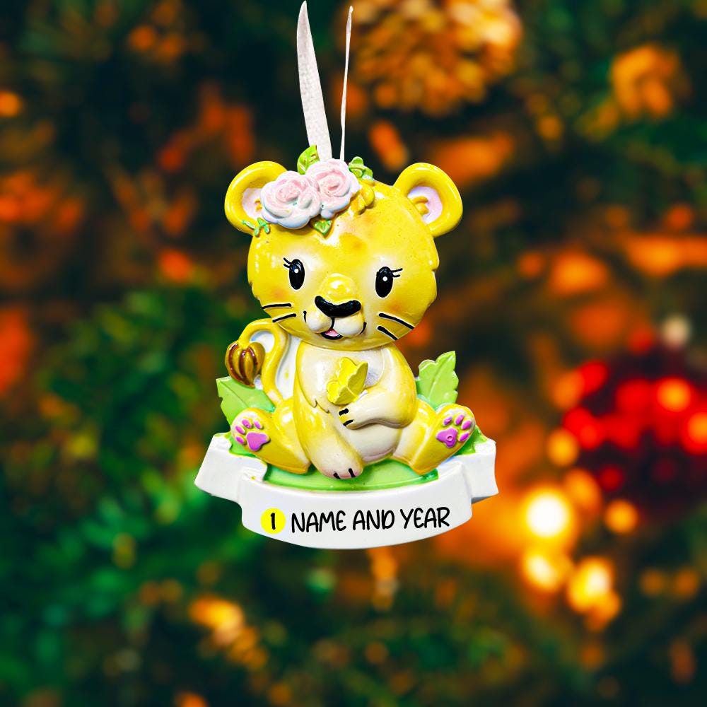 Personalized baby lion Christmas ornament featuring a sweet yellow lion cub wearing a floral crown and holding a small leaf. The bottom banner can be customized with name and year, creating a unique keepsake for a newborn or toddler. Designed in warm yellow and soft pastel tones, this resin baby Christmas ornament is perfect for celebrating Baby’s First Christmas or adding a personalized jungle themed touch to your holiday tree.