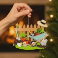 Load image into Gallery viewer, Personalized gardener ornament featuring a detailed garden scene with wooden fence wheelbarrow potted plants gardening tools and soil elements. The design includes a customizable name on the fence and a year on the base making it a thoughtful keepsake for garden lovers. The ornament has a warm rustic farmhouse style and is displayed with a red hanging ribbon suitable for Christmas trees seasonal decor and gift displays.
