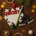 Load image into Gallery viewer, Decorative ornament with 'Hockey' text, skates, and a hockey stick on a wooden surface.
