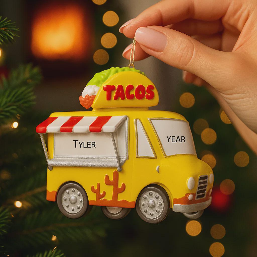 Yellow taco truck ornament with 'Tyler' and 'Year' text, held by a hand against a festive background.