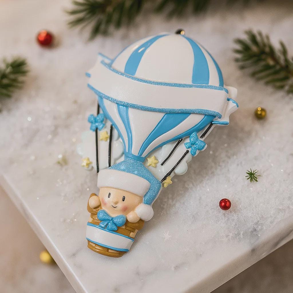 Personalized Baby Boy First Christmas Ornament designed as a charming 3D hot air balloon with a sweet baby in the basket below. The name is featured on the lower section and the year or Baby’s First Christmas message appears on the banner across the balloon. Soft blue and white tones, glitter accents, and raised dimensional details create a playful keepsake. Perfect for newborn boys, baby shower gifts, and celebrating a baby’s first holiday season.