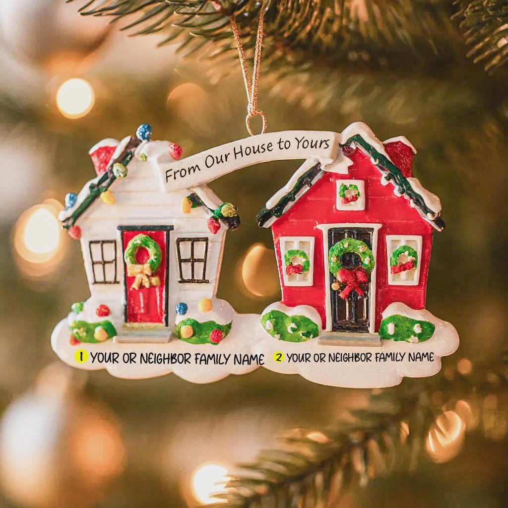 Decorative Christmas ornament with two houses neighbor and personalized text on a blurred Christmas tree background.