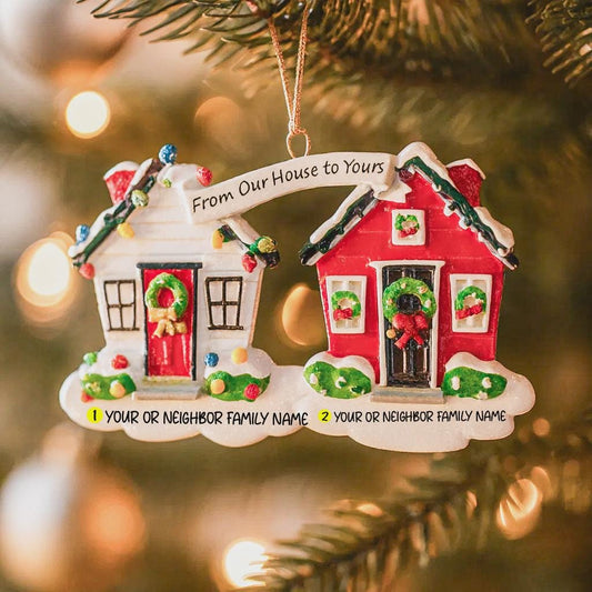 Decorative Christmas ornament with two houses neighbor and personalized text on a blurred Christmas tree background.