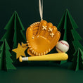 Load image into Gallery viewer, Personalized baseball glove Christmas ornament featuring a tan baseball glove with stitched details, customizable name area on the glove, customizable year star, and customizable text on the baseball bat, glossy finish with raised 3D front details and flat 2D back, white satin hanging ribbon, displayed on a snowy baseball field themed holiday background with baseballs and pine branches.
