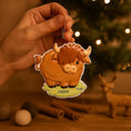 Load image into Gallery viewer, Adorable Highland cow themed Christmas ornament featuring a fluffy brown cow design with soft rounded details and a warm countryside feel. Styled in a natural green meadow setting, this ornament is designed to be personalized and brings a cozy farm inspired charm to holiday tree decor.

