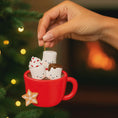 Load image into Gallery viewer, Decorative ornament of a red mug with marshmallows and a cookie, held by a hand against a festive background.
