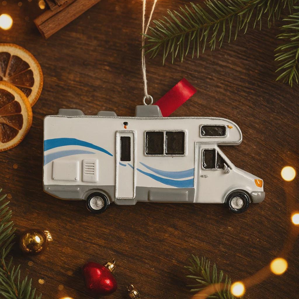 RV-shaped Christmas ornament on a wooden surface with festive decorations.