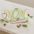 Load image into Gallery viewer, Embroidered design with initials 'Mom' on a white fabric background
