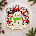 Load image into Gallery viewer, Decorative Christmas ornament with a snowman and penguins on a textured surface with Christmas decorations.
