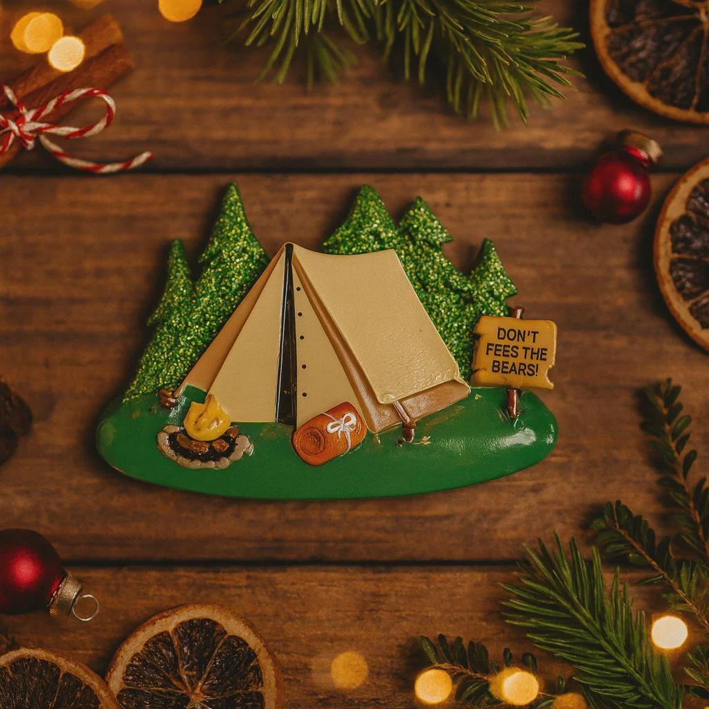 Decorative Christmas ornament with a tent and 'Don't Feed the Bears!' sign on a wooden background.