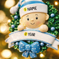 Load image into Gallery viewer, Personalized Baby Boy Christmas Ornament featuring a sweet child peeking from a festive green wreath with blue accents and polka dot bow. This ornament has a raised 3D front design with detailed holly leaves, textured elements, and dimensional lettering. The name is placed on the hat and the year on the banner. A meaningful keepsake for baby’s first Christmas, newborn gift, or holiday memory decoration for the Christmas tree.
