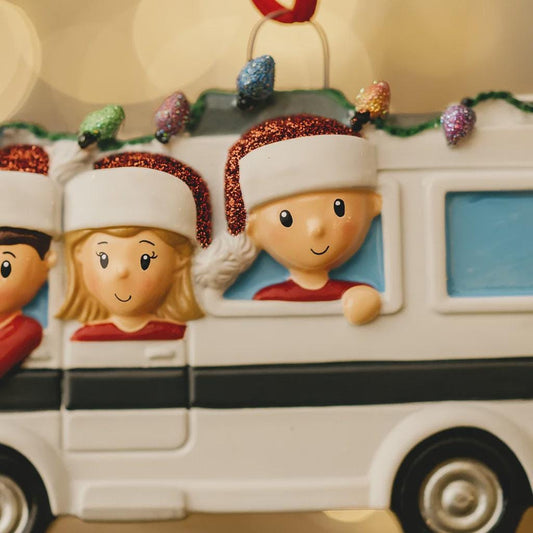 Christmas ornament of a family in a car with Santa hats on a blurred light background