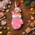 Load image into Gallery viewer, Personalized Baby Girl Christmas Ornament featuring a sweet baby in a pink stocking with raised 3D front details and textured snowflake accents. The name is added on the hat and the year on the stocking, creating a meaningful newborn keepsake. Soft pink tones, holiday elements, and dimensional design make it perfect for baby’s first Christmas, baby girl gift, and special family memory ornament for the tree.
