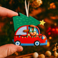 Load image into Gallery viewer, Festive dog themed Christmas ornament featuring a happy puppy riding in a red car with a Christmas tree on top. Designed with playful holiday colors and a cozy winter setting, this ornament brings a joyful pet themed touch to Christmas tree decor. Includes personalization options for name and year, making it a meaningful keepsake for dog lovers and pet families.
