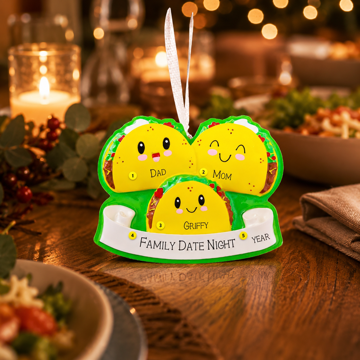 ornament item shaped like a family of tacos on a wooden table with candles and food in the background.