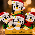 Load image into Gallery viewer, Decorative penguin family ornament with personalized names against a blurred warm background
