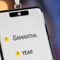 Load image into Gallery viewer, Personalized name tag with 'Samantha' and 'Year' printed on it, against a blurred background.
