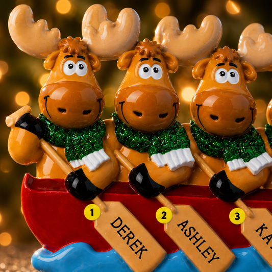 Three moose figurines in a canoe with names on paddles against a blurred background