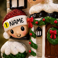 Load image into Gallery viewer, Decorative Christmas ornament with a child wearing a red hat and 'NAME' label, standing in front of a house with wreaths and a lantern.

